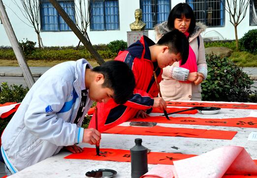 图为 学生书法爱好者书写春联